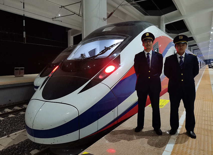 劉銀能（右一）與中國師父鄔俊鴻在動車組前合影。受訪者供圖